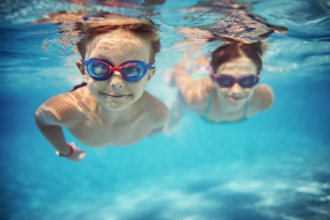 Happy kids swimming underwater in pool stock photo