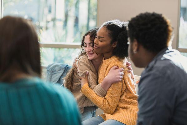 Ci Young Women Embracing in Group Therapy Session