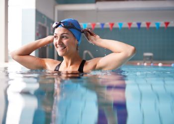 Female Swimmer Wearing Hat And Goggles Training In Swimming Pool stock photo