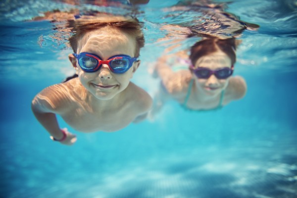 Happy kids swimming underwater in pool stock photo